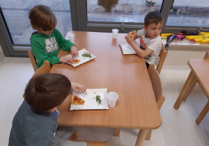 Dzieci jedzą własnoręcznie wykonaną pizzę