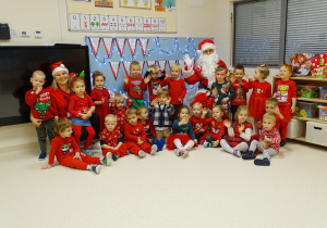 Zdjęcie grupowe ubranych na czerwono Maluchów ze świętym Mikołajem.