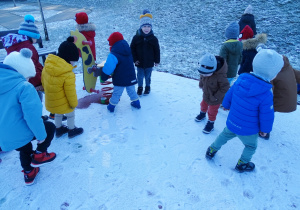 Dzieci robią ślady na śniegu.