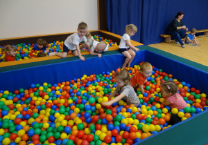 Dzieci bawią się w basenie z kolorowymi kulkami.