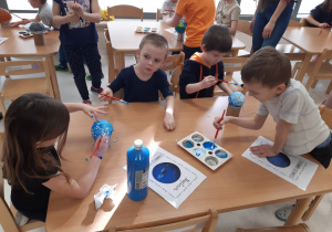 Dzieci malują model Neptuna i Urana