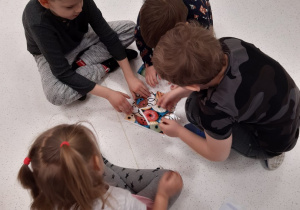 Dzieci w małych grupach układają pączkowe puzzle