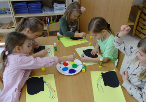 Dziewczynki wykonują pracę plastyczną z wykorzystaniem patyczków i farb