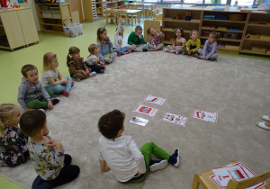 Dzieci siedzą na dywanie i słuchają
