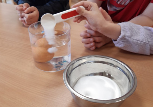 Dziecko nasypuje sól do pojemnika z jajkiem