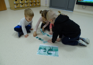 Mikołaj, Blanka, Małgosia i Seba układają puzzle na podłodze.