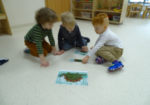 Wojtuś, Ernest, Julek układają puzzle na podłodze.
