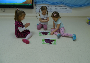 Kinga, Aniela, Julka układają puzzle na podłodze.