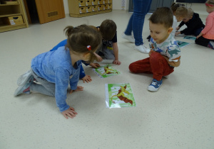 Leoś, Pola, Miłosz i Ksawcio układają puzzle na podłodze.
