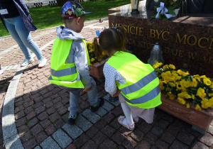 Dzieci składają znicz pod pomnikiem Jana Pawła II