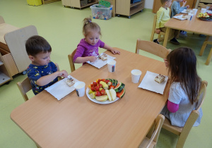 Dzieci jedzą przy stolikach
