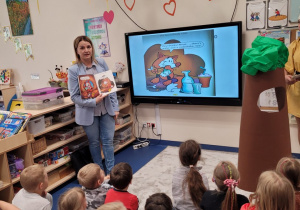Dzieci patrzą na obrazek w książce oraz tablet