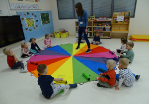 Dzieci grają na dzwonkach według koloru, jaki wskaże nauczycielka na chuście.