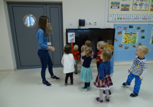 Dzieci stoją z nauczycielką i mrówką - gościem przy obrazku z zebrami.