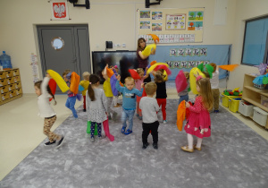 Dzieci z panią tańczą trzymając w rękach kolorowe chusty.