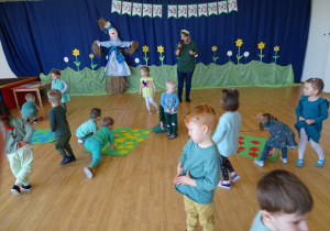 Dzieci układają na zielonych kartonach kolorowe kwiaty.
