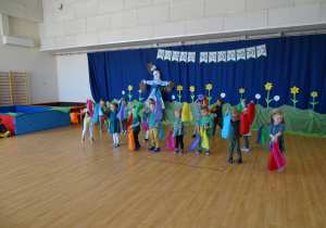 Dzieci tańczą na sali gimnastycznej trzymając w rękach kolorowe wstążki.