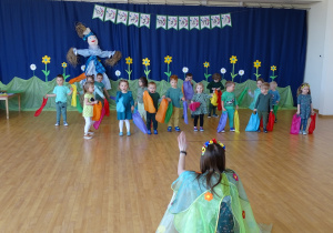 Dzieci tańczą na sali gimnastycznej trzymając w rękach kolorowe wstążki.
