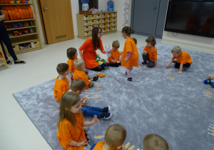 Dzieci siedzą w kole ubrane na pomarańczowo. Blanka karmi królika.