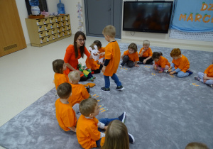 Dzieci siedzą w kole ubrane na pomarańczowo. Franio karmi królika.