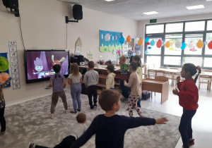 Dzieci tańczą na dywanie przed tabletem