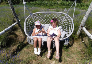Maja i Iza siedzą na huśtawce z bukiecikami lawendy