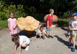 Dzieci pozują przy ogromnym modelu grzyba kurka