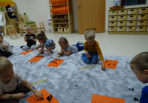 Dzieci dmuchają bibułę przez słomki.