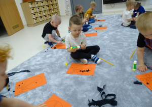 Dzieci przyklejają bibułę na sylwety biedronek.