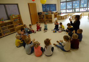 Dzieci siedzą w kole i klaszczą.