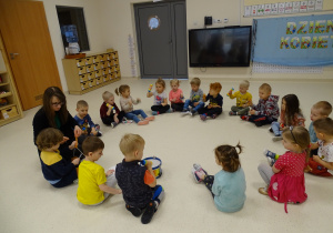 Dzieci siedzą w kole i grają na instrumentach.