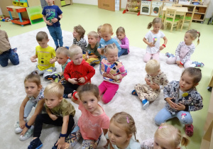 Dzieci siedzą na podłodze i pokazują, gdzie mają brzuch.