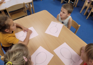 Dzieci przy stoliku z kartami przedstawiającymi balon