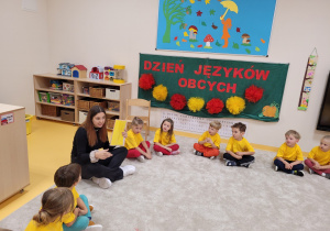 Uczennica pokazuje dzieciom kartkę w kolorze żółtym