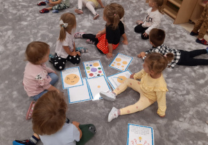Dzieci siedzą wokół ilustracji z kropkami