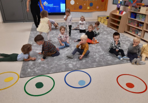 Dzieci siedzą naprzeciwko kolorowych obręczy