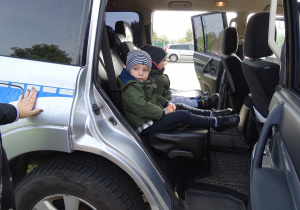 Dzieci mają możliwość wejścia do samochodu policyjnego.