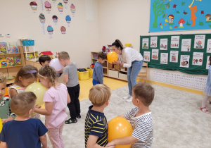Dzieci trzymają balon pomiędzy głowami