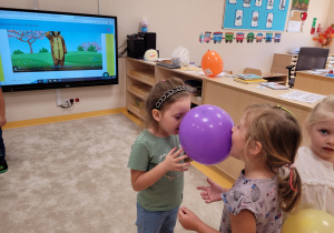 Dzieci trzymają balon między nosami