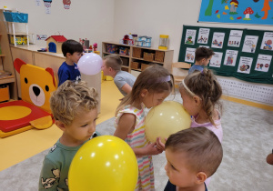Dzieci w parach trzymają balon za pomocą ust
