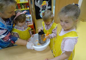Alicja ściera marchewkę na tarce.