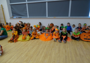 Dzieci w pomarańczowych strojach siedzące na podłodze
