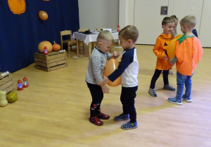 Dzieci tańczą w parach z pomarańczowym balonem pomiędzy brzuszkami