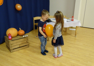 Dziewczynka i chłopiec tańczą w parze z balonem