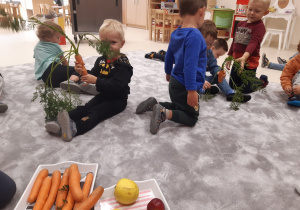 Dzieci oglądają marchewkę, przekazują sobie z rąk do rąk