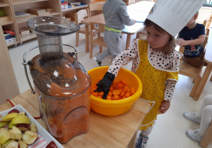 Natalka wkłada marchewkę do sokowirówki
