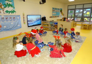 Dzieci siedzą na podłodze z prezentami