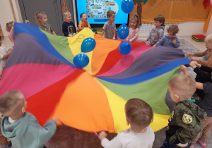Dzieci podrzucają niebieskie baloniki na chuście animacyjnej