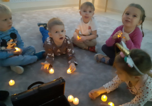Dzieci trzymają w rączkach zapalone świeczki na baterie
