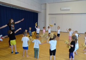 Dzieci ćwiczą na sali gimnastycznej ze swoimi misiami - krążenie ramion.